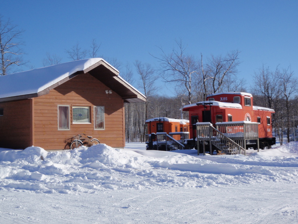 Photo taken by Ellen Smith of the west end of the Candy Store cabin and Orange and Red Caboose on a bright sunny day.